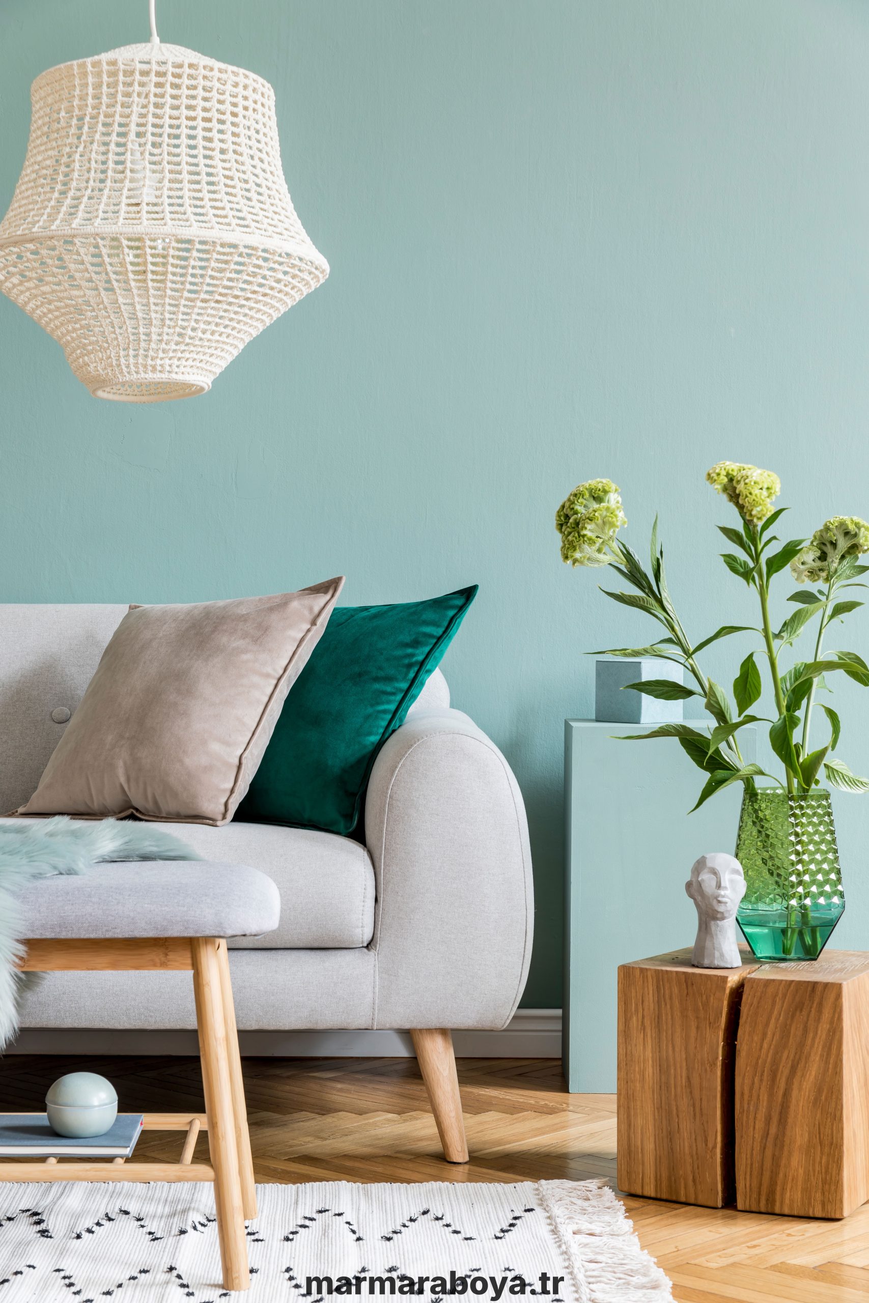 Stylish composition of cozy living room with sofa, wooden cube, nice interior details and neutral classy pillows. Green and grey creative wall and parquet floor. Scandinavian style.